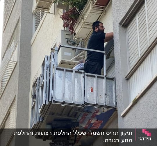 אדם על מנוף מתקן תריסים בבניין
